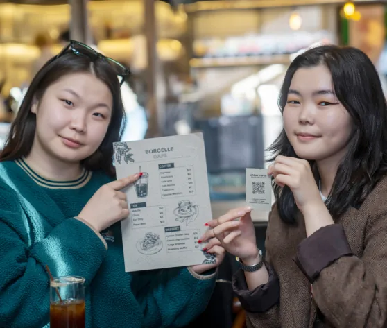 Two café guests holding a menu printed on argal paper