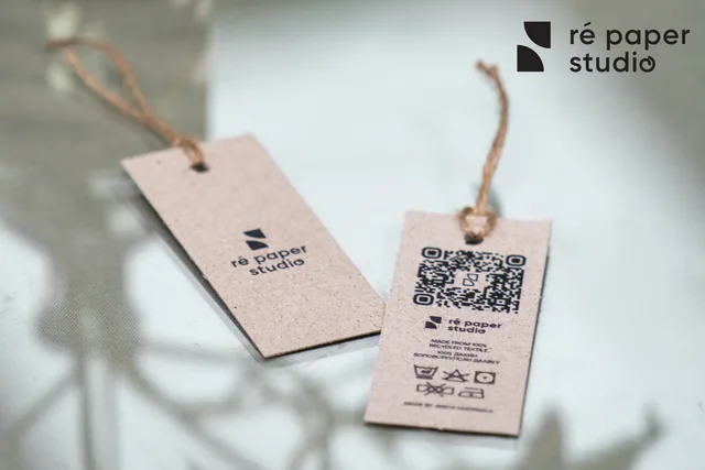 Two small hang tags on jute twine with logo, QR code and care symbols